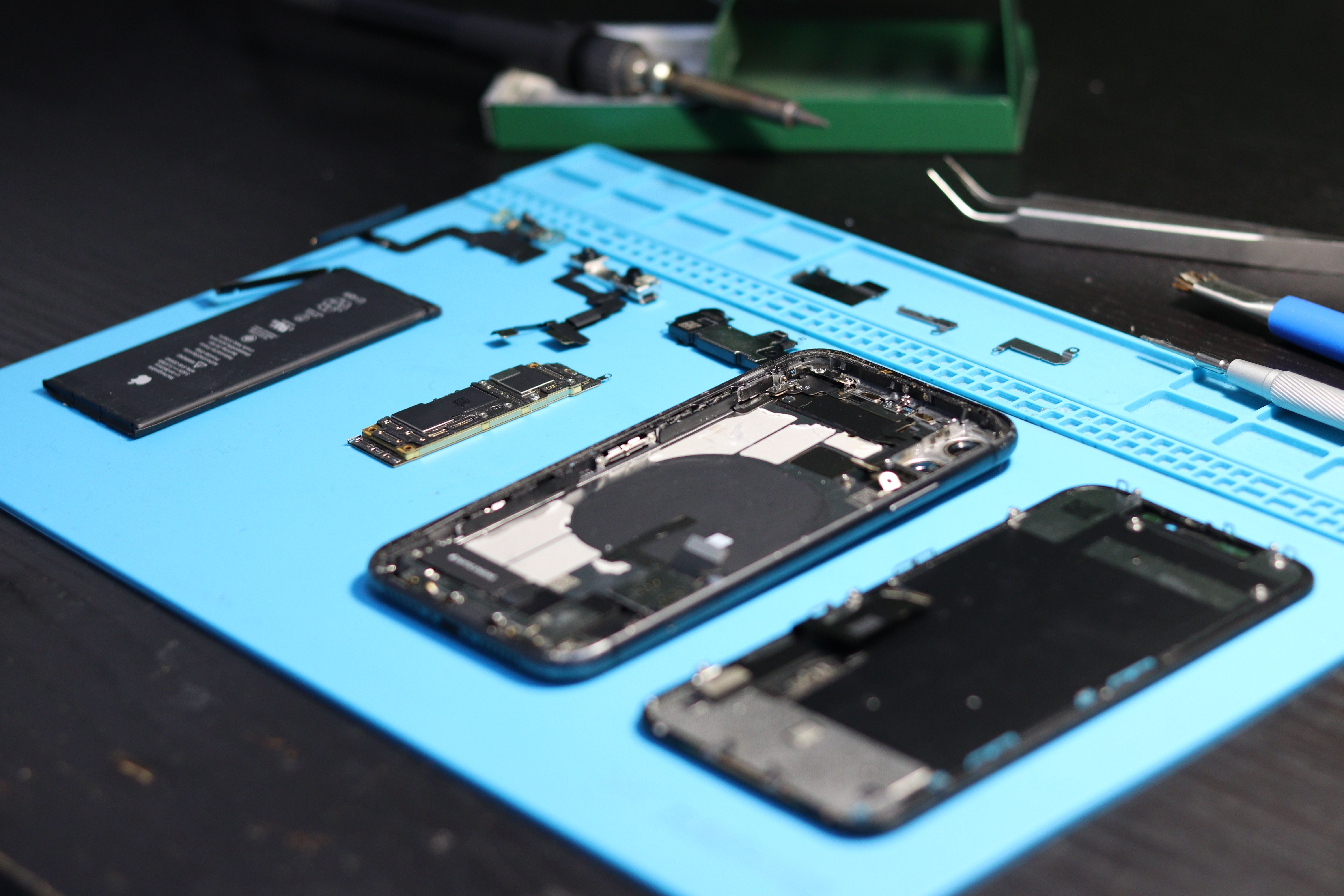 Genuine phone repair parts — screens, batteries, boards and tools laid out on a repair bench